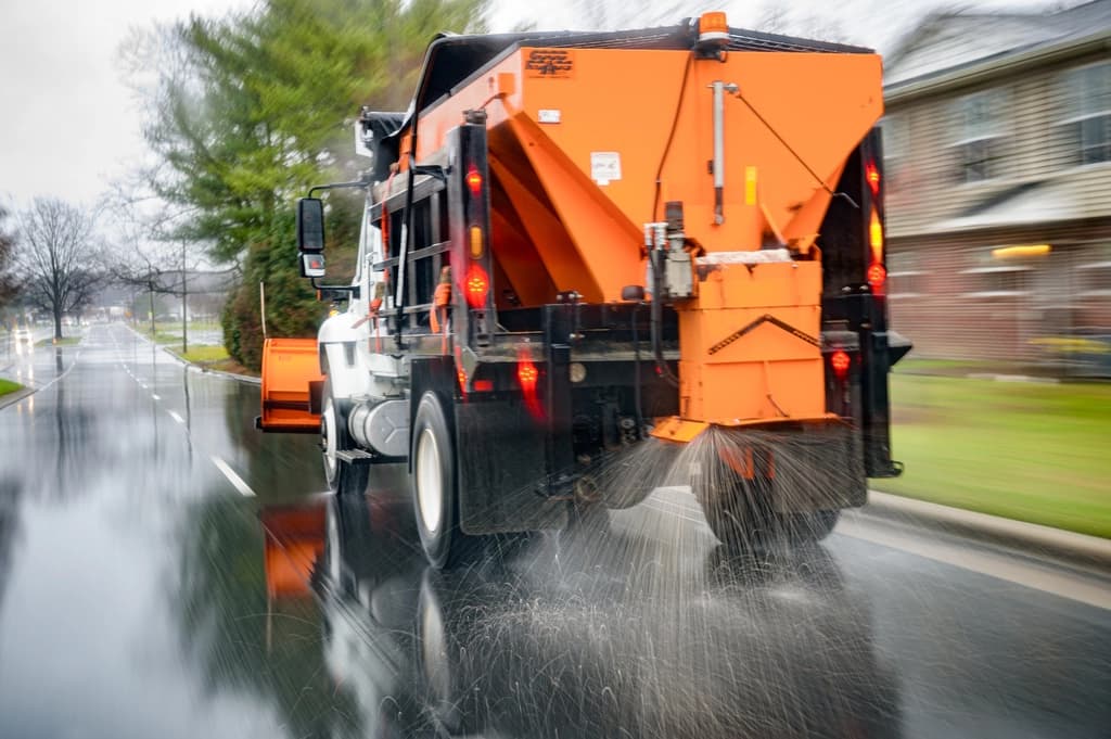 Spreader truck applying salt brine to a wet road to prevent ice