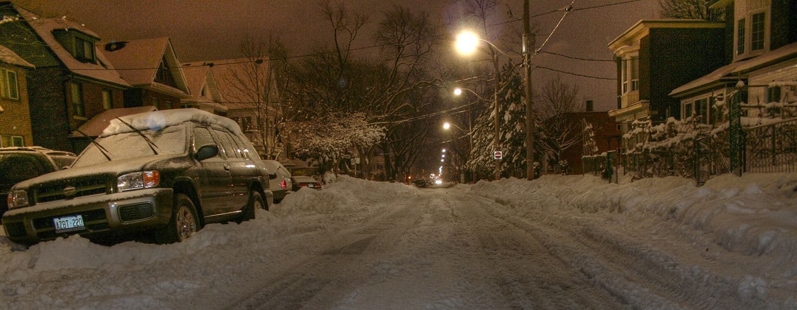 Ontario residential street and parked cars buried in snow at night after a winter storm